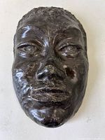Front view of dark glazed ceramic face mask sculpture