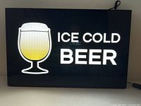 Front view of illuminated sign showing text and beer glass graphic