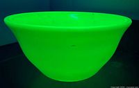 Bowl glowing under UV light showing uranium glass characteristic
