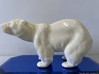 Full left side view of ceramic polar bear on blue base