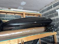 Full view of black Thule roof cargo box stored on shelf