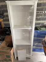 Front view of white bookcase wrapped in plastic film