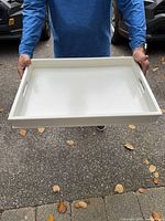 Top perspective of white tray held by person showing full rectangular shape
