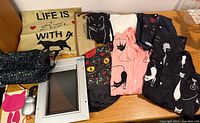 Full lot overview showing shirts, bags, pillowcase, cat door, scratch pad, cat toy