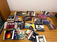 Wide view of multiple stacks of CD booklets and tray cards spread on desk