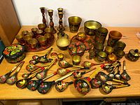 Full layout of painted wooden spoons, cups, bowls, tray and candlesticks on tabletop