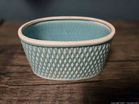 Front view of oval turquoise ceramic planter showing diamond lattice texture
