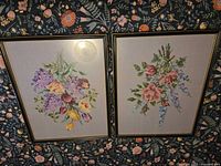 Both framed needlepoint pieces shown side by side on patterned surface
