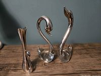 front view of two bubble glass swans and silver-plated bud vase
