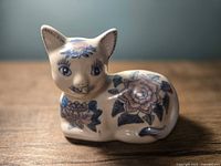 Front view of ceramic cat coin bank showing floral design