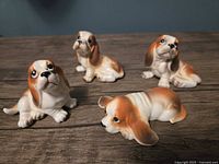 Four porcelain Basset Hound figurines on wood surface, assorted poses