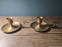 Pair of brass chamber candlesticks front view on wooden surface