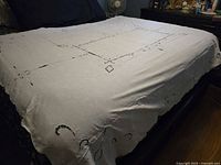 Overall view of tablecloth spread on bed showing size and central cutwork design