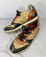 Top and lateral view of both sneakers showing canvas, leather, snakeskin trim and rivets