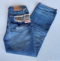 Pair of Diesel jeans folded showing back pocket, tags and leather patch