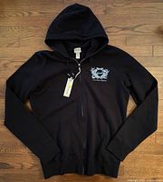 Front view of hoodie laid flat showing overall style and tags attached