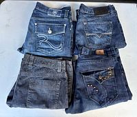 Four pairs of folded jeans showing back pockets and washes