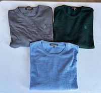 Three folded sweaters showing colors and identical style