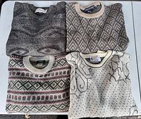 Four folded sweaters showing patterns and colours