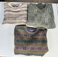 Three folded sweaters showing overall colors and patterns