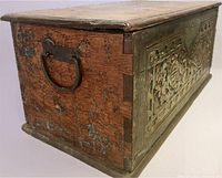 Three-quarter view showing carved panel, side handle, dovetail joints, paint traces