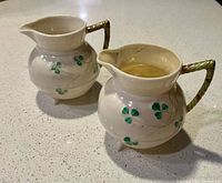 Front angled view of both Belleek Shamrock creamers showing pattern and handles