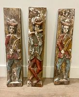 All three carved wood panels standing upright