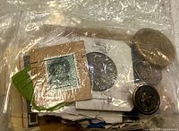 Mixed coins, stamps and a button inside zip-lock bag