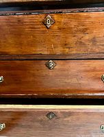 Close-up of two drawers showing brass keyhole plates and wood grain