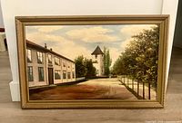 Framed oil painting leaning against wall showing full artwork and frame