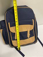 Front of navy/tan picnic backpack with tape for height reference