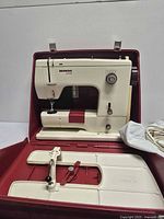 Full view of sewing machine inside red case with extension table