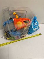 Bag containing assorted toy tools with tape measure for scale