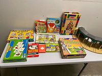 Overview of all boxed games, wooden blocks set, train shed, and puzzles on table