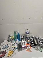 Group shot of entire lot showing main items including Stanley thermos, GE lantern, travel flask set, glass bottles, produce bags and accessories