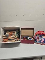 Overall lot showing box of wooden railway pieces, box of trains, and Mega Bloks carry bag