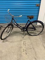Full side view of blue Raleigh ladies bicycle with basket, kickstand down