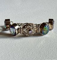 Front view of entire bracelet showing oval iridescent stones and central filigree piece