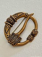 Front view of circular bronze brooch showing design details