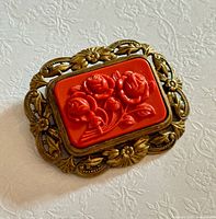 Front view showing brass frame and red celluloid floral plaque