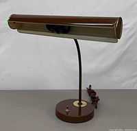 Front view of brown metal desk lamp showing cylindrical shade, upright stem, round base