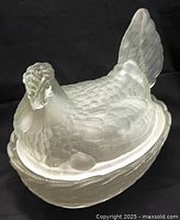 Side view of frosted glass hen on nest dish showing feather detail and basket base