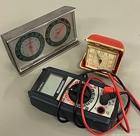 Group shot of the three items: thermometer-hygrometer, travel alarm clock, digital multimeter with leads