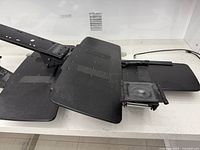 Two keyboard tray assemblies showing overlapping black platforms and wrist rests attached to articulating arms