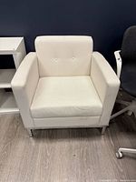 Front view of white faux leather armchair showing tufted back, square arms, chrome legs