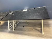 Single desk close-up showing tabletop, legs, wear