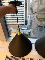 Close view of one pendant light held up to show underside and cord connection