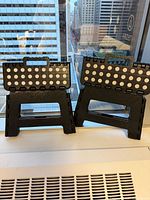 Two identical black folding step stools with polka-dot tops placed on windowsill