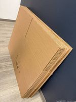 Stack of flat brown cardboard boxes leaning against wall