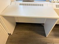 Front view of white desk showing top surface and panel legs